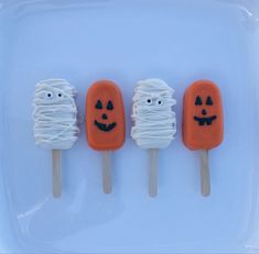 three pops with marshmallows decorated as jack - o'- lantern faces