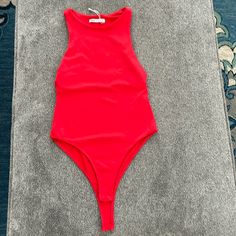 a red one piece swimsuit laying on the ground