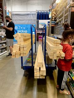 two children are playing with wooden blocks in the store while an adult looks at them