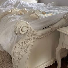 a white bed sitting on top of a wooden floor next to a dresser and mirror