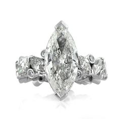 an oval cut diamond engagement ring with three side stones on the band and two claw prongs