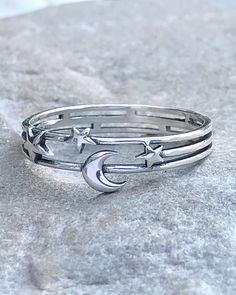 Moon and Stars Silver Ring | The Life Divine Moon and Stars Layered Cut Out Sterling Silver RingThe Moon is a feminine symbol and represents the light that shines within each of us. She reminds us that all things on earth have a natural cycle.The stars which light up the evening sky inspire us to dream. Sterling SilverRing measures 1/4". Adjustable Celestial Star-shaped Rings, Symbolic Moon-shaped Adjustable Rings, Adjustable Moon Shaped Symbolic Rings, Adjustable Moon Shaped Celestial Rings, Adjustable Moon-shaped Celestial Rings, Celestial Stackable Promise Rings, Celestial Style Stackable Rings As Gift, Celestial Adjustable Midi Rings, Magical Moon Shaped Ring With Moon Phase Detail