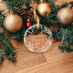 a personalized ornament hanging from a christmas tree with pine cones and ornaments