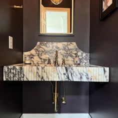 a bathroom sink with marble counter top and gold faucet