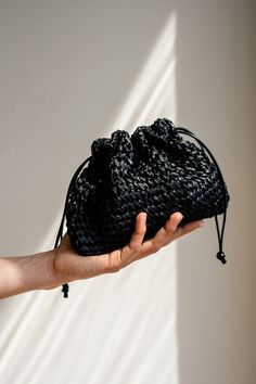 a hand holding a small black bag in it's palm