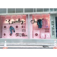 a pink storefront with clothes hanging on the front and in the window, there is a sign that says laundry shop