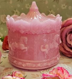 a pink glass container sitting on top of a table next to flowers and a lace doily