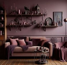 a living room with purple walls and furniture in the corner, including a couch that has pillows on it