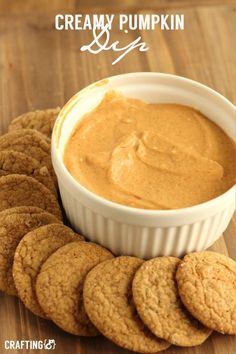 a bowl of peanut butter surrounded by cookies on a wooden table with the words creamy pumpkin dip