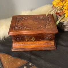 a wooden box sitting on top of a table next to a vase filled with flowers