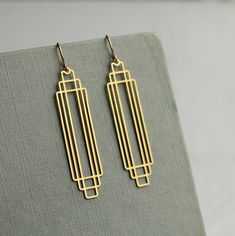 These great earrings are made with solid brass and feature a graduated art deco design.  They remind us of classic Deco architecture, like the Chrysler building!   The earrings measure 45mm (just under two inches) in length and have gold plated ear wires.   They have been designed and made in our Edinburgh studio.   This piece of handmade jewellery comes packaged in a nice recycled gift box with a handmade tag, all ready to give or keep. We also have these earrings in silver, as well as  many other Art Deco designs!  🖤 FASTER SHIPPING 🖤 Need this fast? We offer a Faster Shipping option here: https://www.etsy.com/uk/listing/100107311/faster-shipping-priority-post-upgrade 🖤 GIFT MESSAGE & WRAP SERVICE! 🖤 https://www.etsy.com/uk/listing/750160511/gift-wrap-wrapping-personalised-card?ref=l Art Deco Jewelry Rings, Art Deco Inspired Jewelry, Cement Jewelry, Art Deco Jewellery Design, Gold Art Deco Earrings, Art Deco Jewellery, Bijoux Art Deco, Silk Purse, Minimalist Earrings Gold