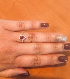 a woman's hand with a ring on top of it and a wooden table in the background