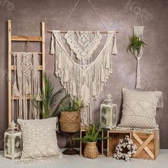 a room with some plants and pillows on the floor next to a wall hanging from a ladder