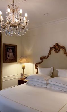 a bedroom with a chandelier and white bedding