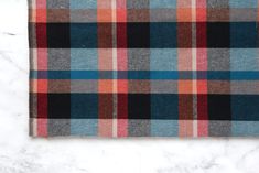 an orange, blue and black plaid blanket on a marble surface