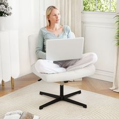 a woman sitting in a chair with a laptop on her lap looking at the screen