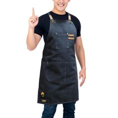 a young man wearing an apron and giving the peace sign with his hand while standing in front of a white background