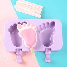 an ice tray with two popsicle molds and a baby foot on it next to toothpicks