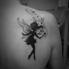 the back of a woman's shoulder with a black and white fairy tattoo on it