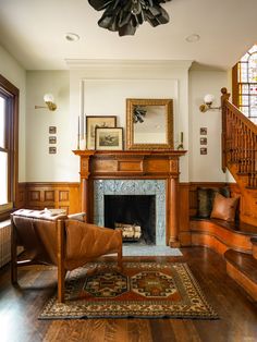 a living room filled with furniture and a fire place under a chandelier on top of a hard wood floor