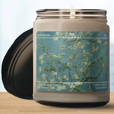 a candle is sitting on a table with a blue background and an almond blossoming tree