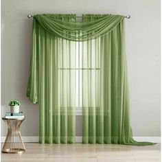 a living room with green curtains and a small table in front of the curtained window