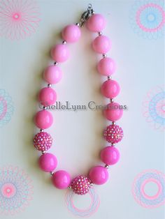 a pink beaded necklace on a white surface with flowers and circles around the beads