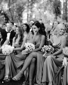 a group of women sitting next to each other in front of a crowd at a wedding