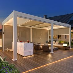 an outdoor kitchen and living room are lit up at night with lights shining on the deck