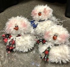 three white fuzzy snowmen with bows on their heads are sitting on the ground next to each other