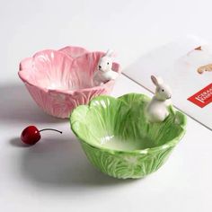 two ceramic bowls sitting on top of a table next to each other, one with an animal figurine in it