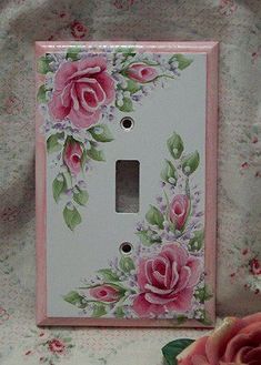 a light switch cover with pink roses painted on it and flowers around the bottom half