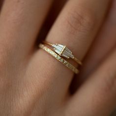 a woman's hand with two gold rings on it and one diamond ring in the middle