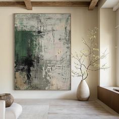 an abstract painting hangs on the wall next to a white vase with flowers in it