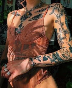 a woman with lots of tattoos on her arm and chest is posing for the camera