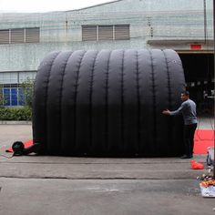 a man standing next to a giant inflatable object on the ground near a building