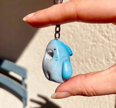 a hand holding a blue elephant keychain with a chain around it's neck