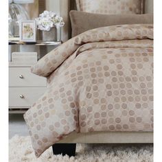 a bed with a beige and brown polka dot comforter set on top of it