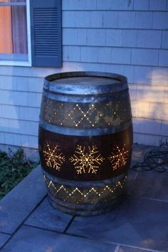 a wine barrel with snowflakes on it sitting in front of a house at night