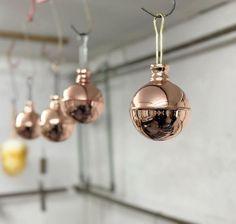 three shiny ornaments hanging from hooks in a room