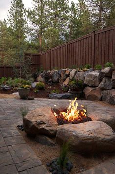 an outdoor fire pit surrounded by rocks and plants