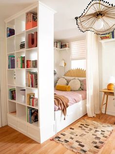 a bedroom with a bed, bookshelf and rugs on the wooden floor