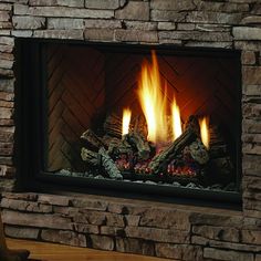 a dog sitting on the floor in front of a fire place with logs and flames