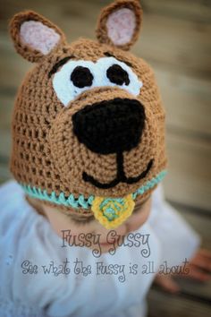 a baby wearing a crocheted hat with a dog's face on it