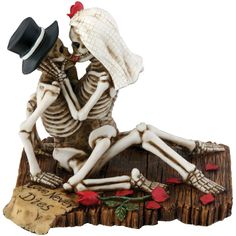 a skeleton figurine sitting on top of a piece of wood holding a woman's head