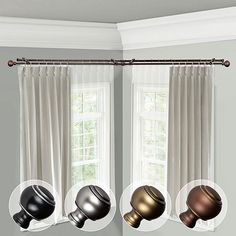 three different shades of metallic balls hanging from a curtain rod in front of two windows