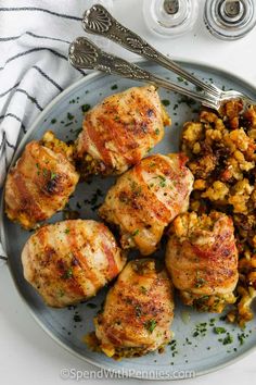 chicken and stuffing served on a plate with two silver serving utensils next to it