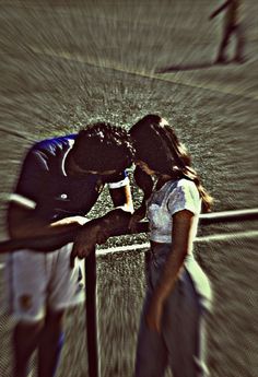 a man and woman kissing on the side of a tennis court with water pouring over them