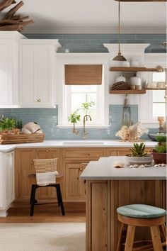 a kitchen with white cabinets and blue backsplashes on the walls, wooden stools in front of an island