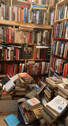 many books are stacked on top of each other in a room full of bookshelves